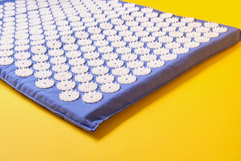 Acupuncture massage mat on yellow background copy space